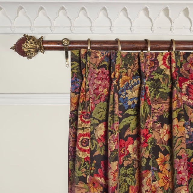 Black-ground velvet curtain with rust, pink, blue and ochre floral blooms in gathered folds