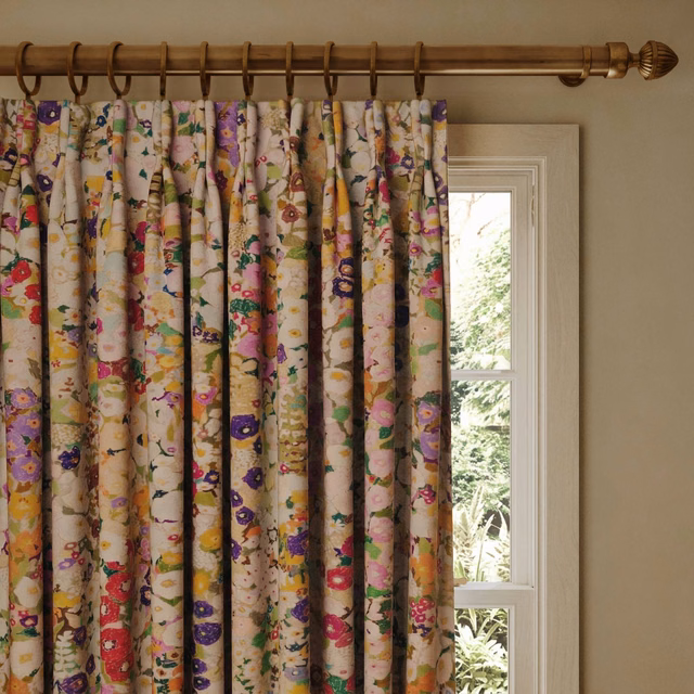 Cream velvet curtain with pink, purple and yellow hollyhock blooms in deep folds