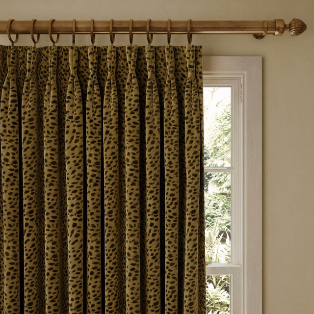 Olive-gold velvet curtain with irregular black animal spots in deep gathered folds