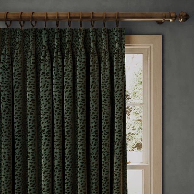Deep forest-green velvet curtain with dark organic spots in gathered vertical pleats