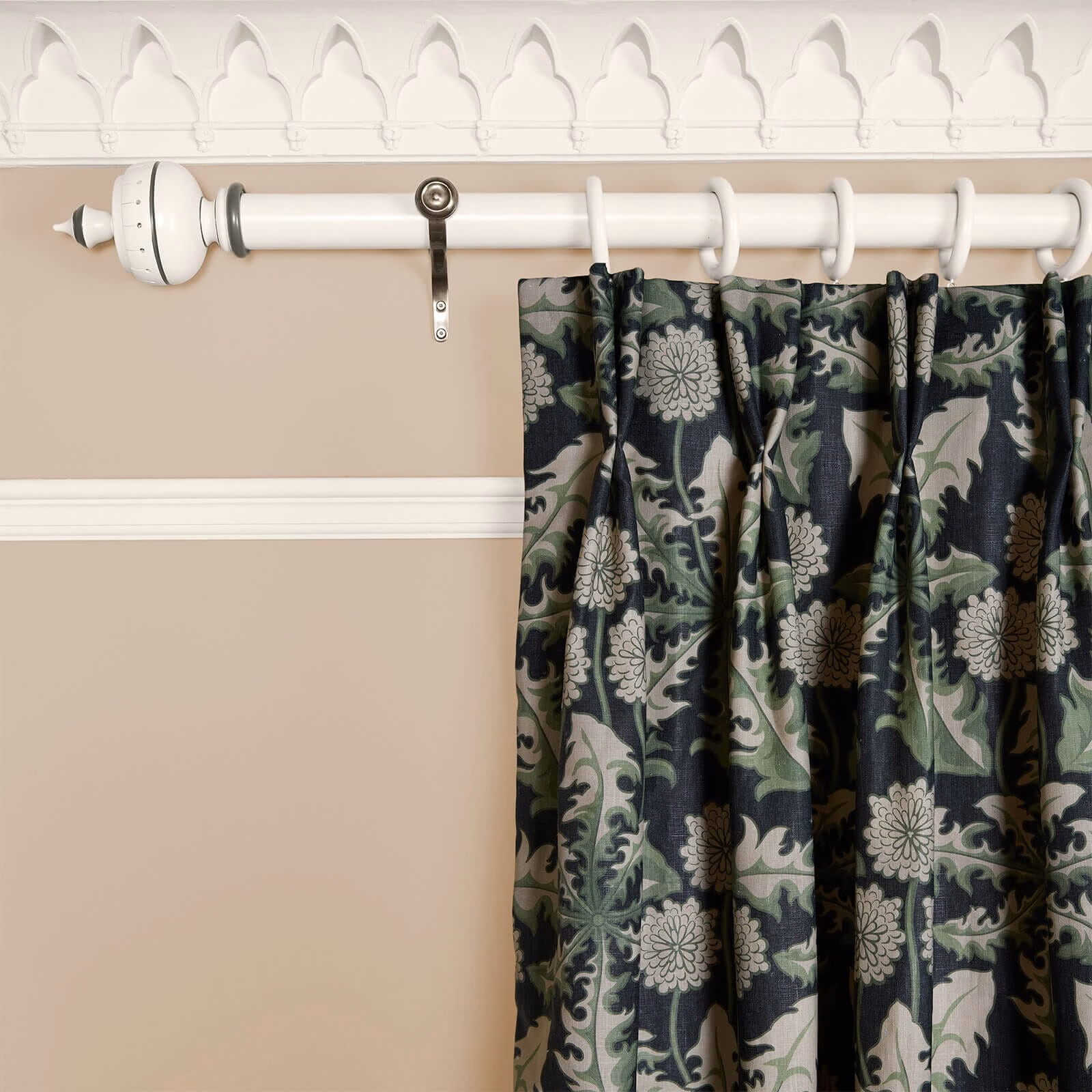 Gathered Noir curtain with sage foliage and pale flowers on a charcoal ground