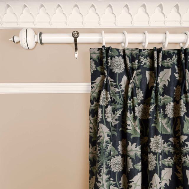 Gathered Noir curtain with sage foliage and pale flowers on a charcoal ground
