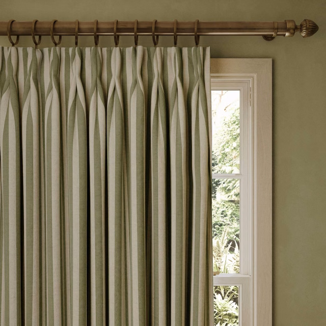 Muted verdigris and ivory undulating stripe jacquard curtains beside a bright window