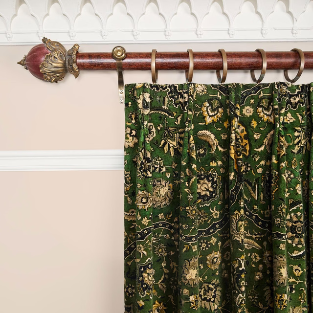 Deep juniper-green velvet curtain with cream and antique-gold floral motifs in gathered folds