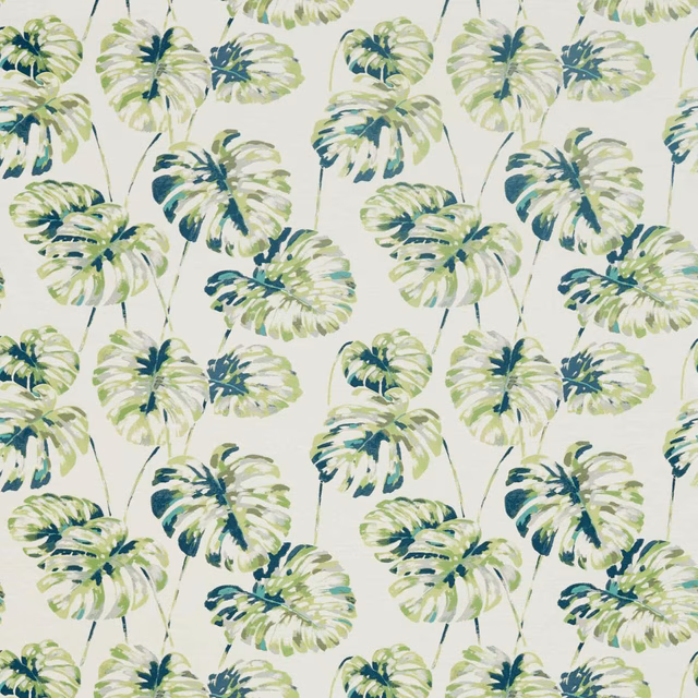 Emerald and zest monstera leaves scattered across an ivory fabric ground