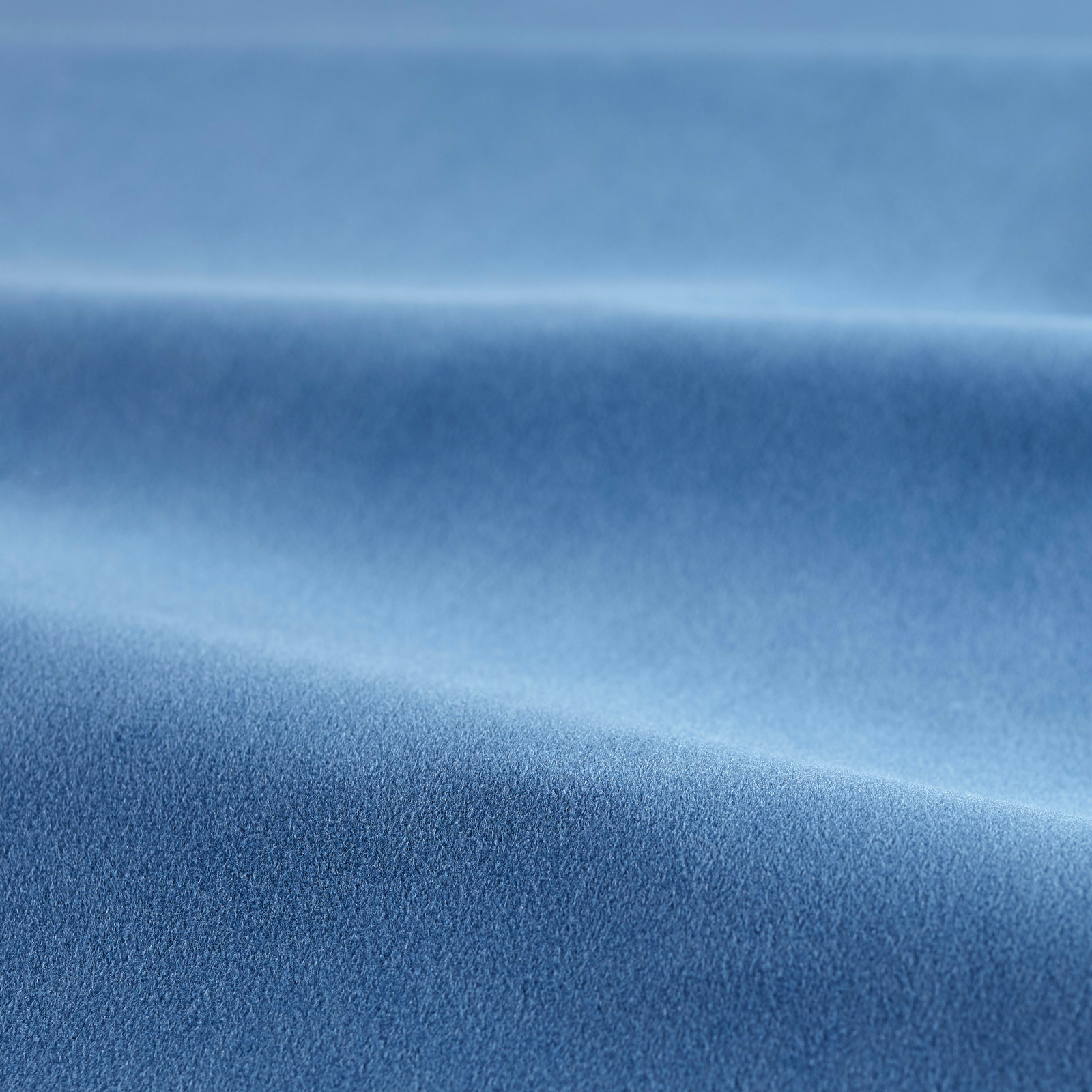 Cool cornflower-blue velvet showing soft pile, directional sheen and folded tonal shading
