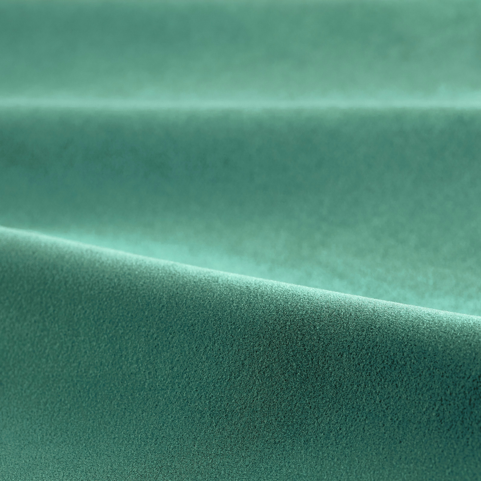 Close-up of emerald green velvet with a plush pile and luminous folded highlight