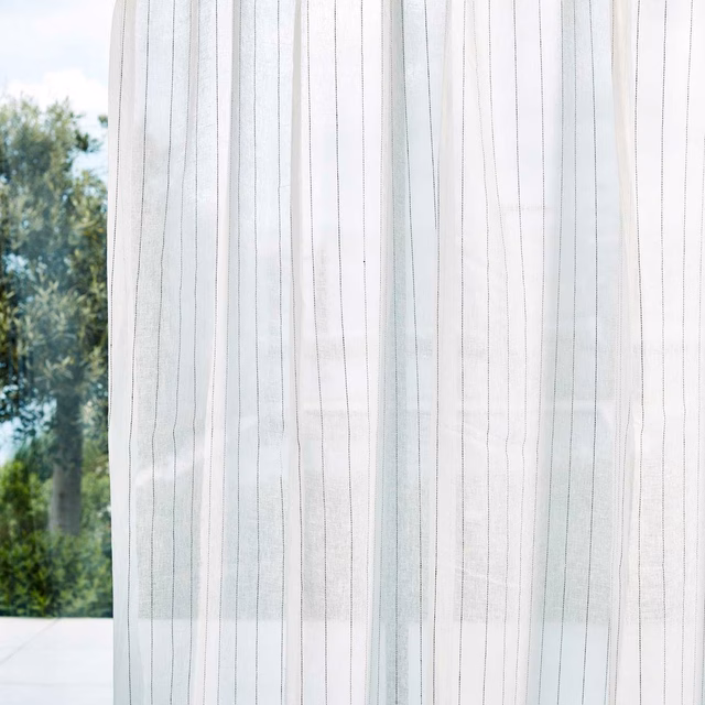 Chalk sheer curtain with fine charcoal vertical lines filtering a garden view