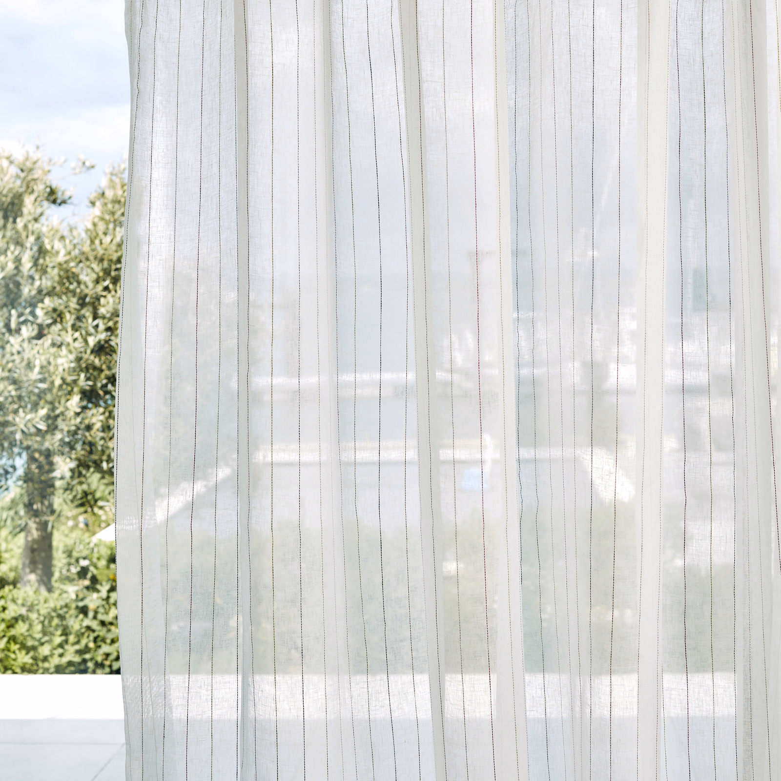 Chalk sheer with delicate mixed-toned vertical pinstripes glowing against a window