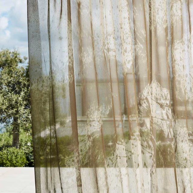 Warm nectar-beige sheer curtain with ivory organic marks and garden light filtering through