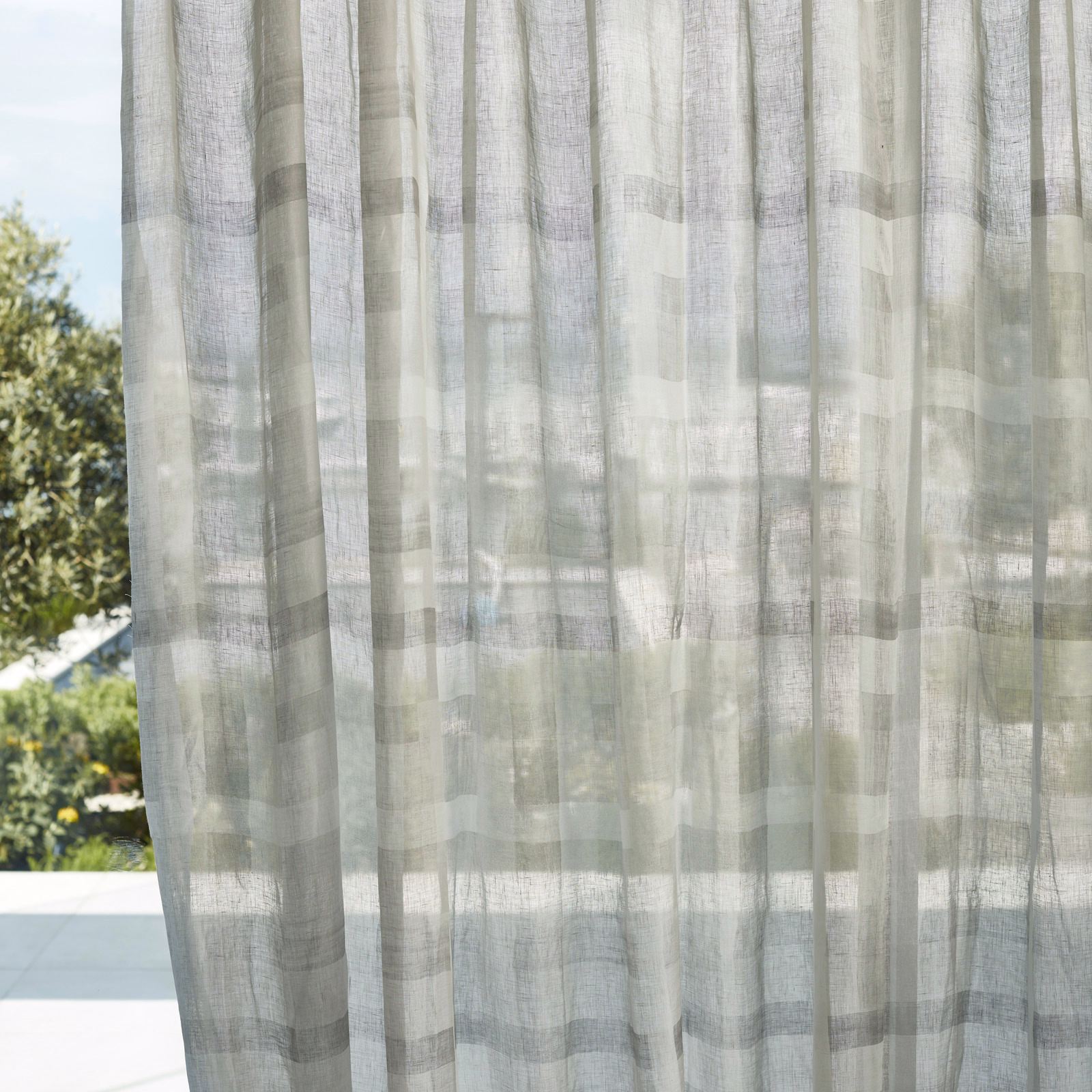 Pale grey-green sheer curtain with translucent woven checks and soft vertical folds
