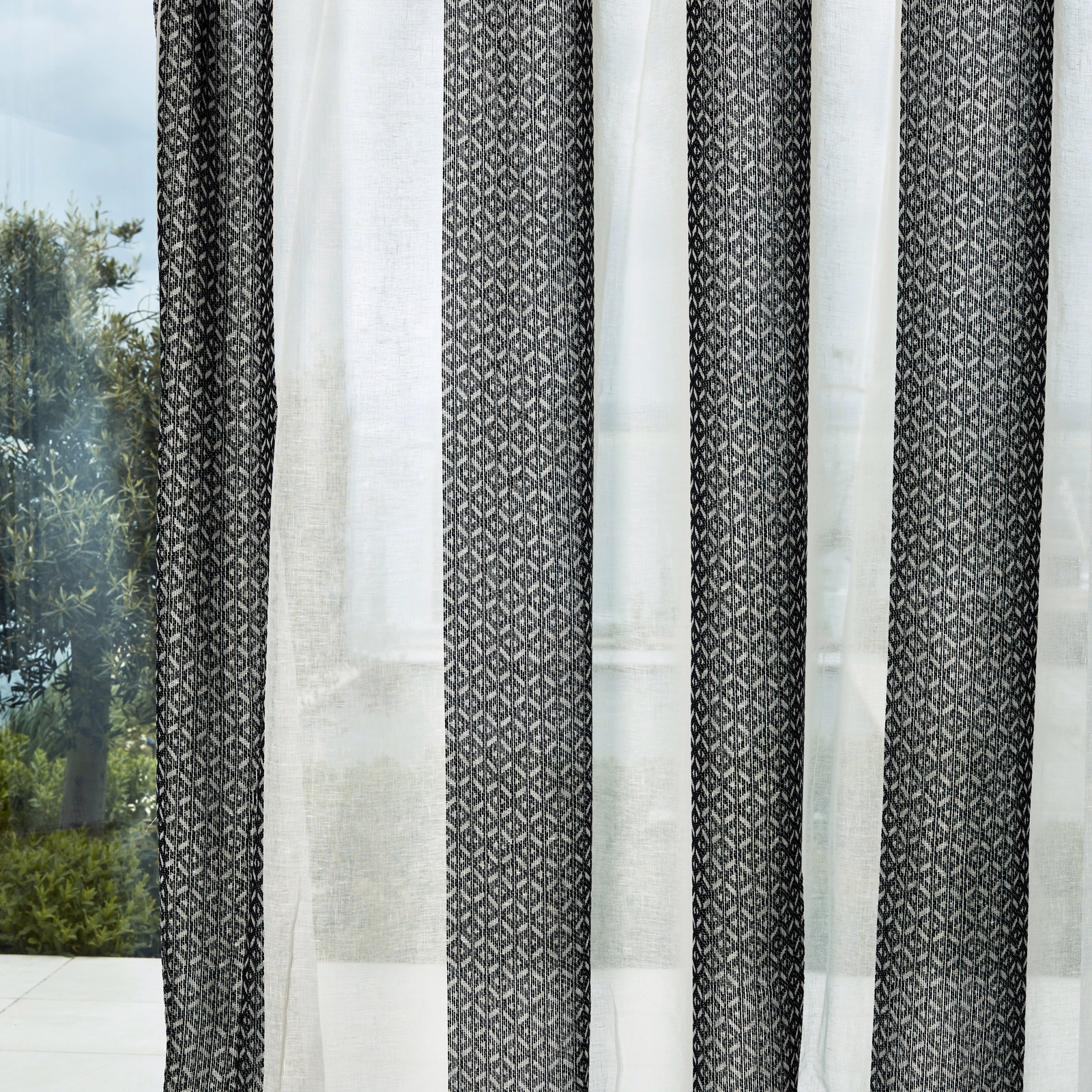 Chalk sheer curtain with black-earth geometric bands and translucent open texture