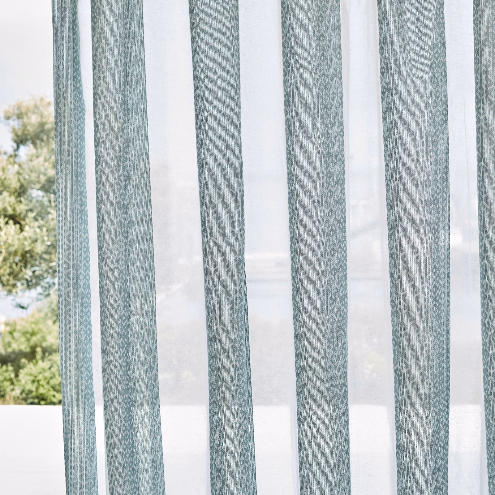 Pale blue-grey sheer with a fine linked geometric motif hanging in soft vertical folds