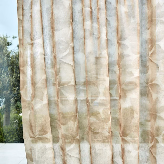 Warm parchment sheer curtain with translucent taupe leaf motifs in soft vertical folds