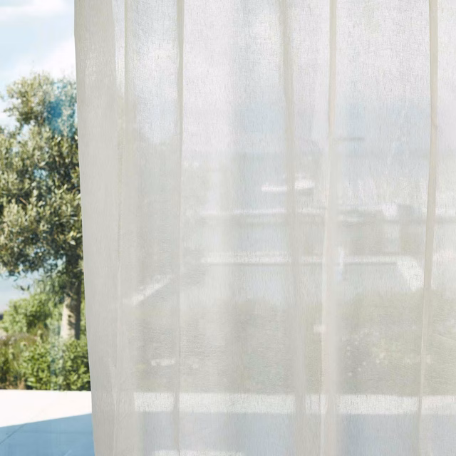 Translucent chalk-white sheer with fine vertical weave filtering a sunlit garden view