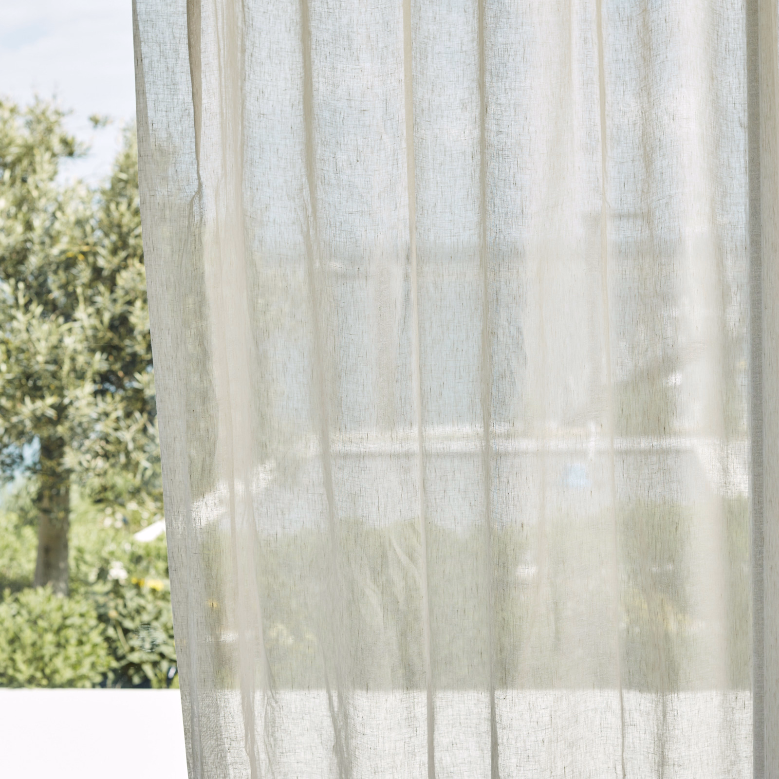 Warm parchment sheer with fine vertical weave, softly filtering a garden view