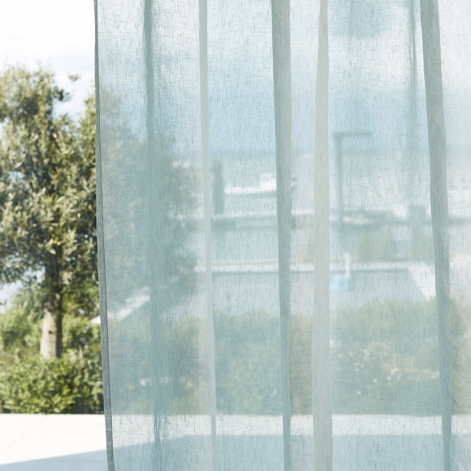 Pale sea-glass sheer curtain with fine vertical weave filtering garden light