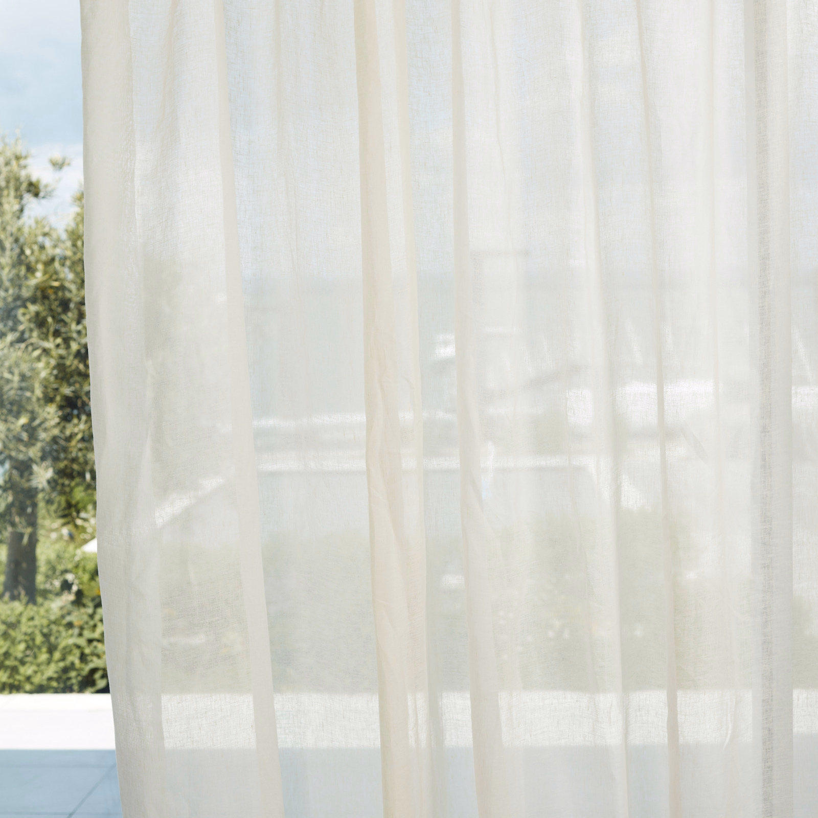 Soft ivory sheer curtain with fine vertical texture filtering daylight at a window