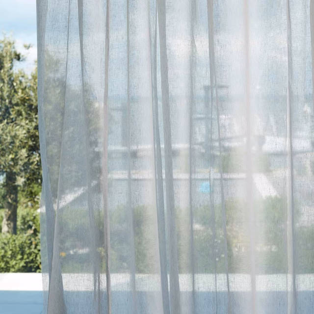 Pale blue-grey sheer with fine vertical weave filtering daylight across a window