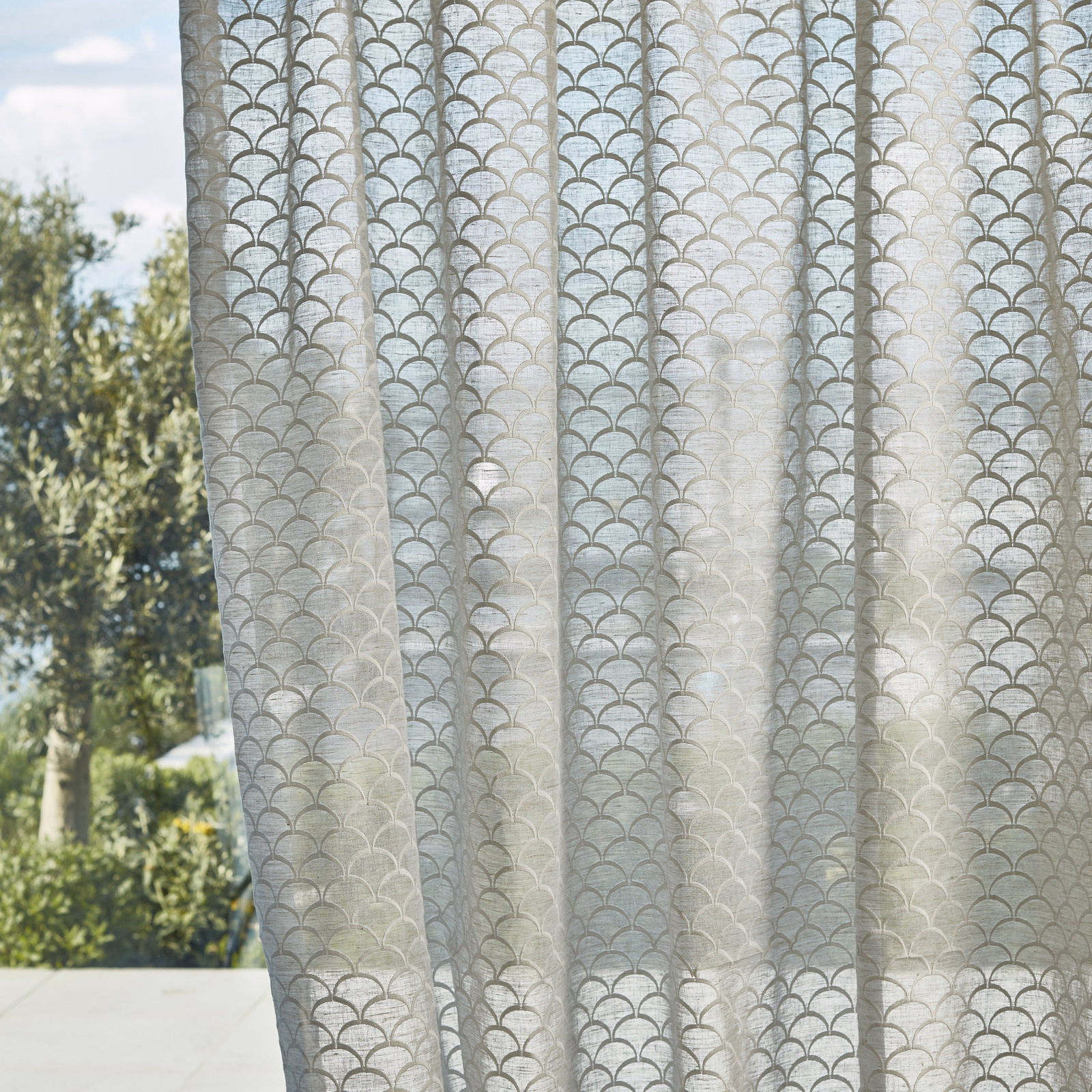 Pale taupe-grey sheer curtain with repeated scalloped arches and translucent folds