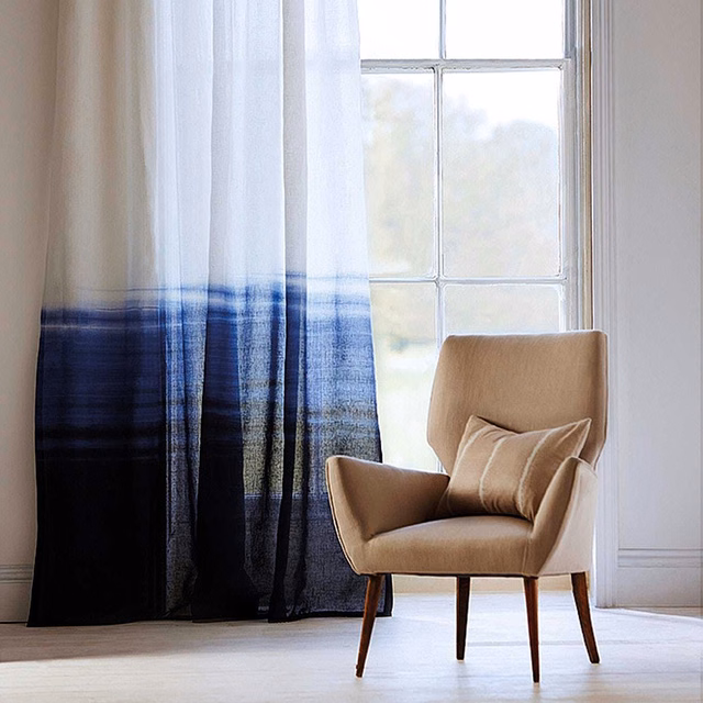 Cool indigo and denim ombré sheer curtain with fine vertical striations by a sunlit window
