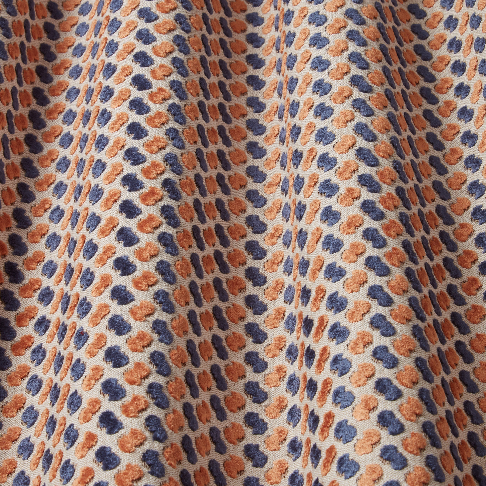 Textured velvet swatch with midnight blue and rust wavy spots on a pale ground