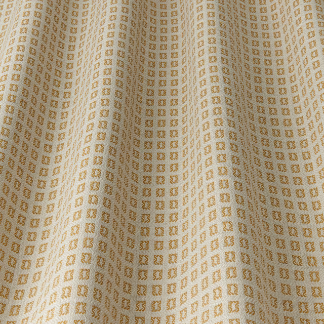 Mustard gold geometric fabric with tiny square motif on a cream ground