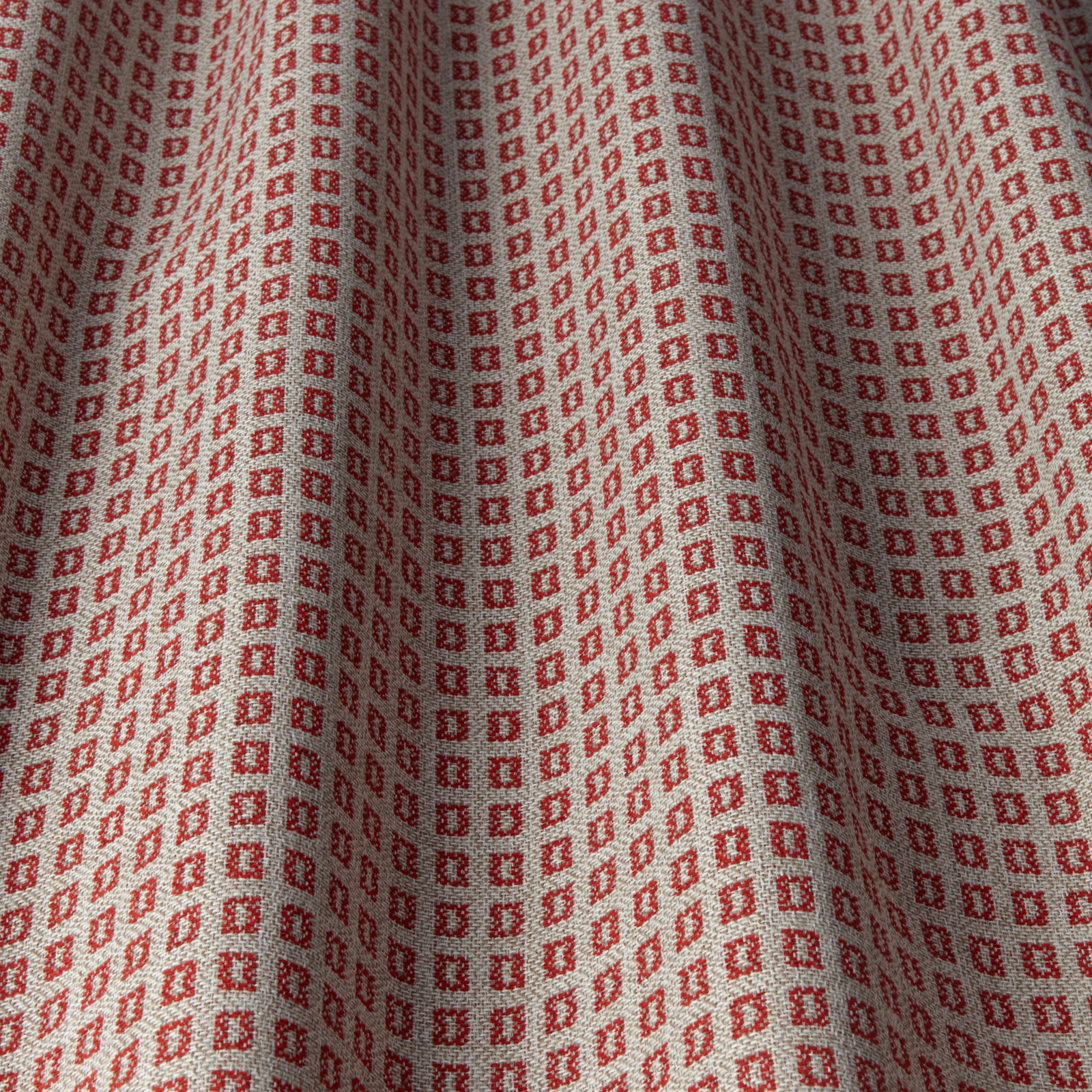 Ruby red small square geometric fabric with a pale background in soft folds