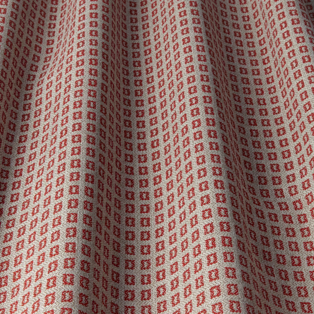 Ruby red small square geometric fabric with a pale background in soft folds
