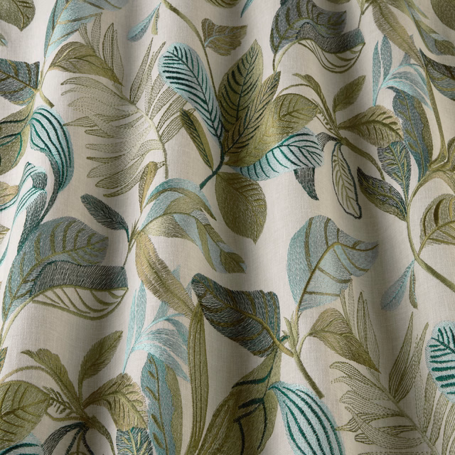 Leafy pistachio, teal and aqua patterned fabric on a soft ivory ground