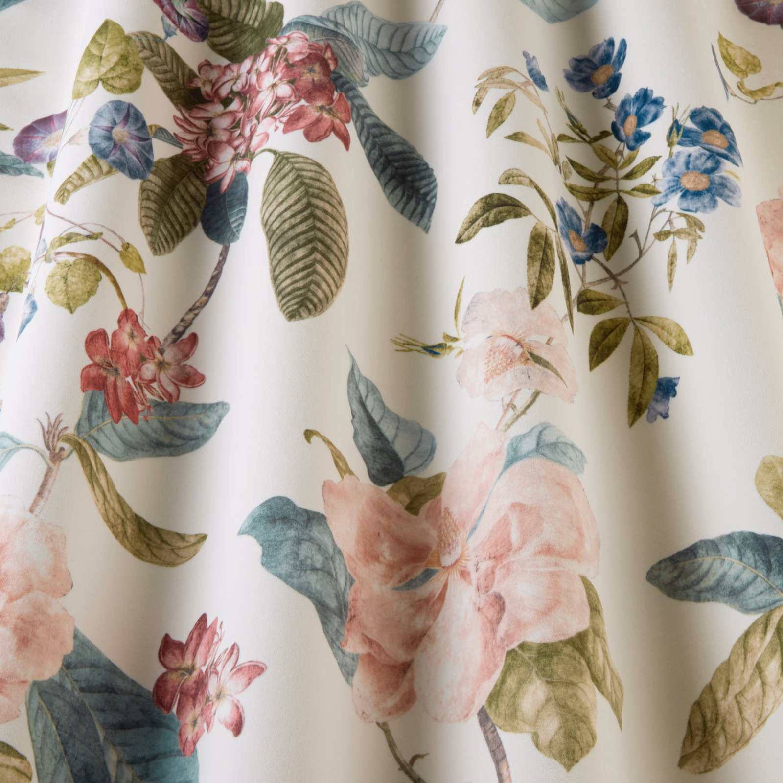 Cream botanical fabric with large blush and blue floral print and green leaves
