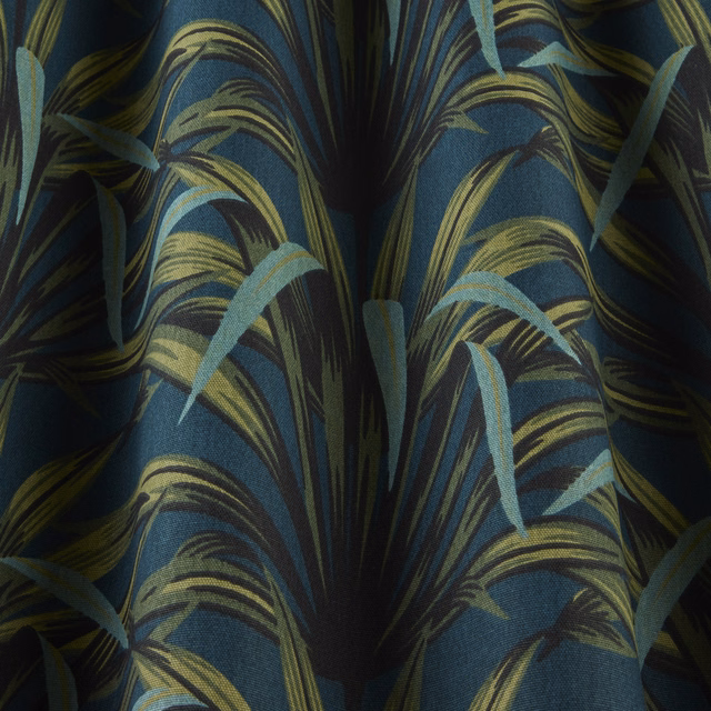 Close-up of deep teal patterned fabric with lime and aqua sweeping leaf-like waves