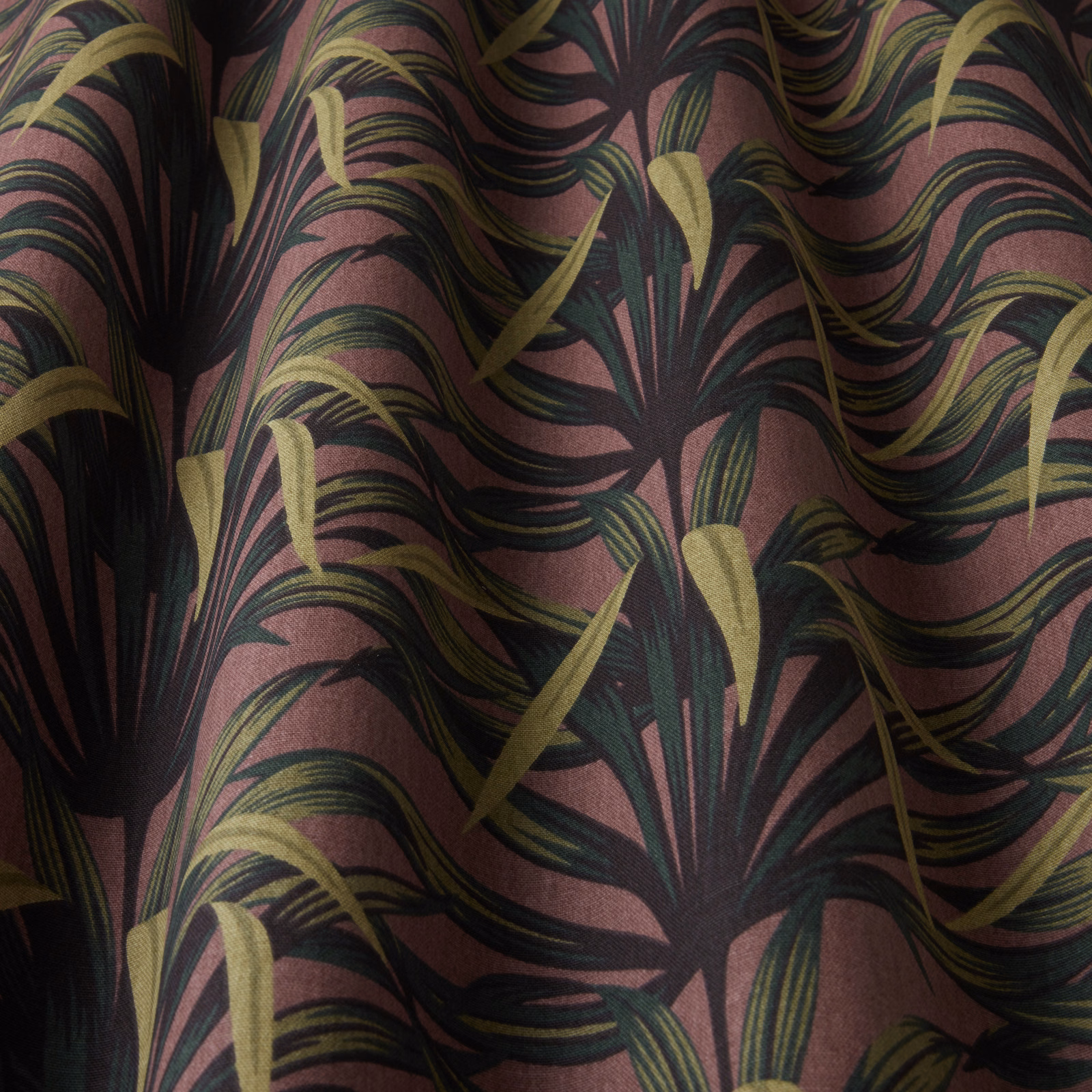 Damson pink botanical fabric with sweeping dark leaves and olive accents