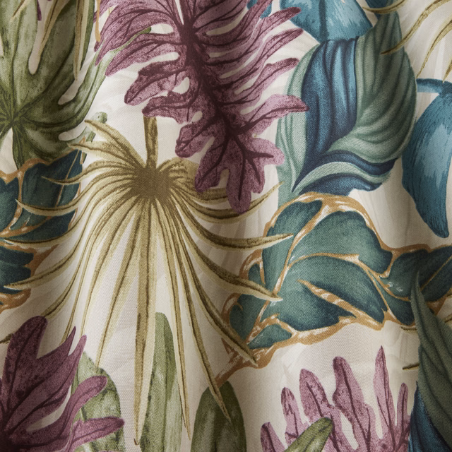 Close-up of botanical fabric with damson plum leaves, teal foliage and ivory ground