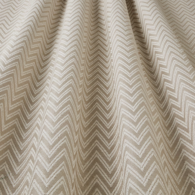 Stone taupe zigzag woven fabric with soft cream geometric stripes, draped in folds