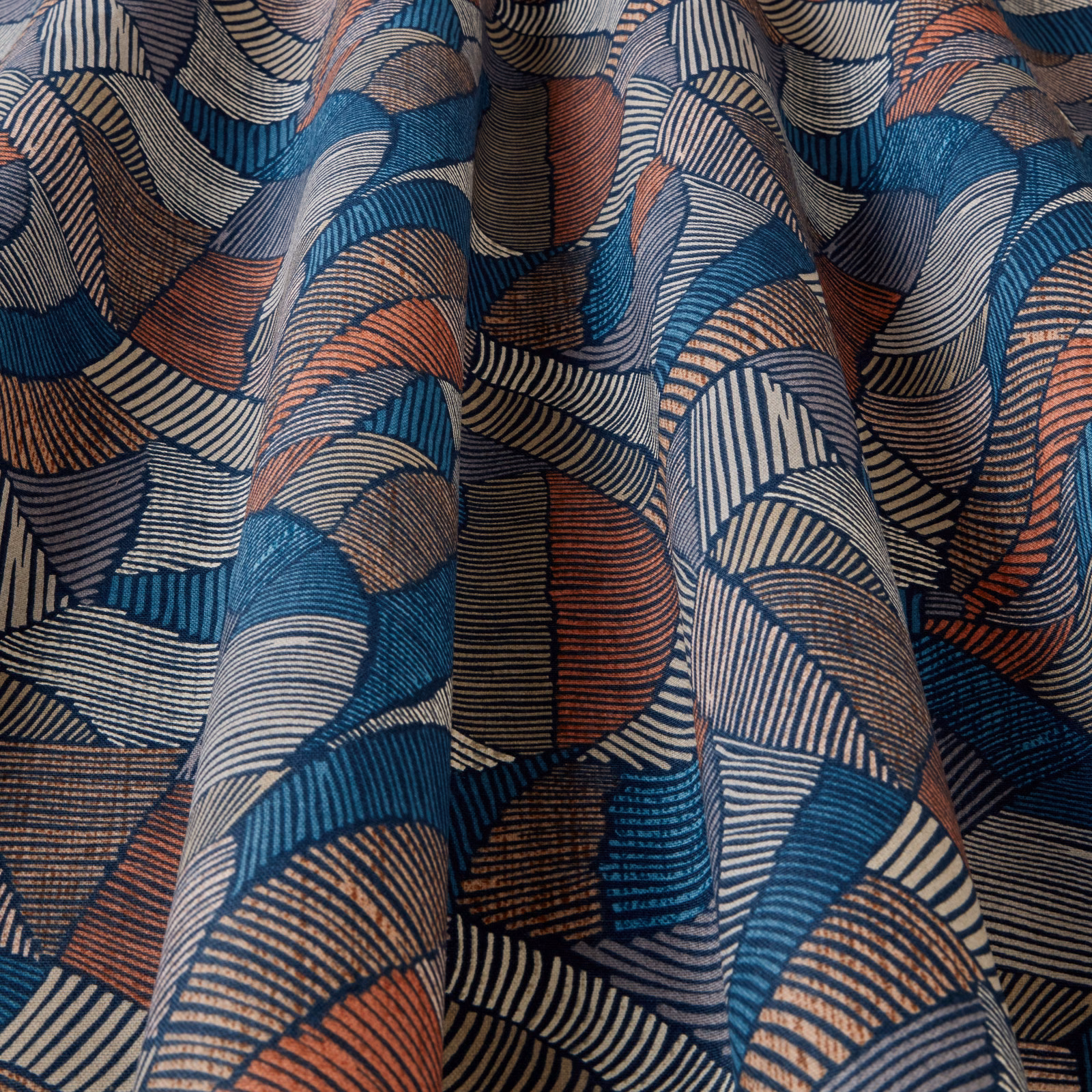 Folded geometric fabric with navy, teal, cream and terracotta wave stripes