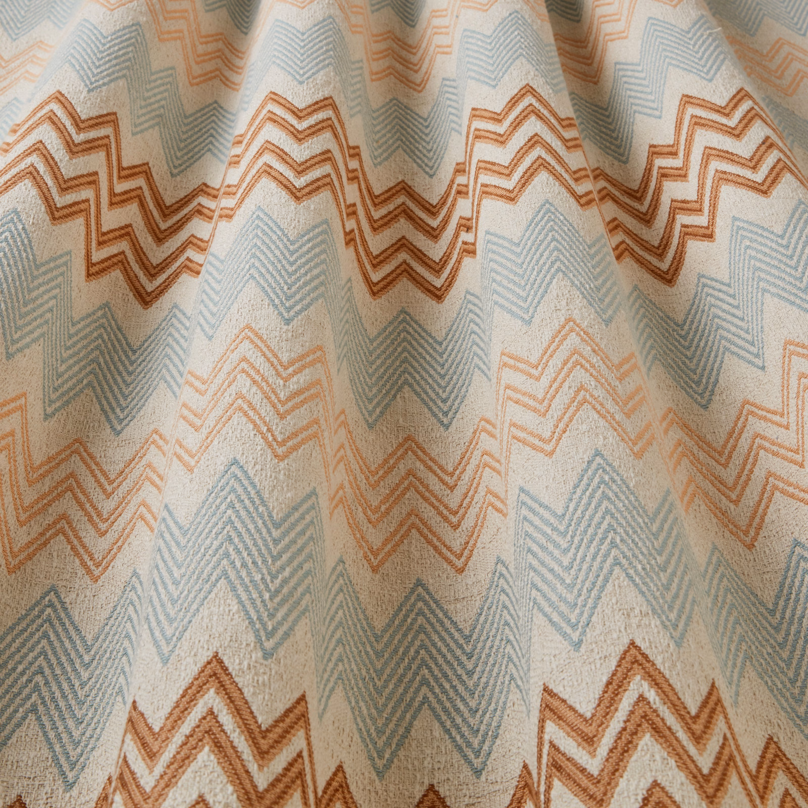 Cream fabric with large aqua and mandarin zigzag chevrons draped in soft folds