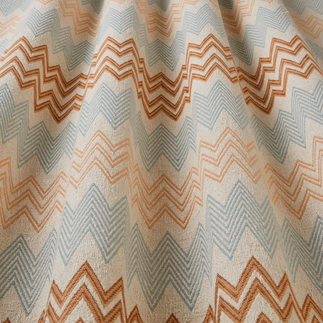 Cream fabric with large aqua and mandarin zigzag chevrons draped in soft folds