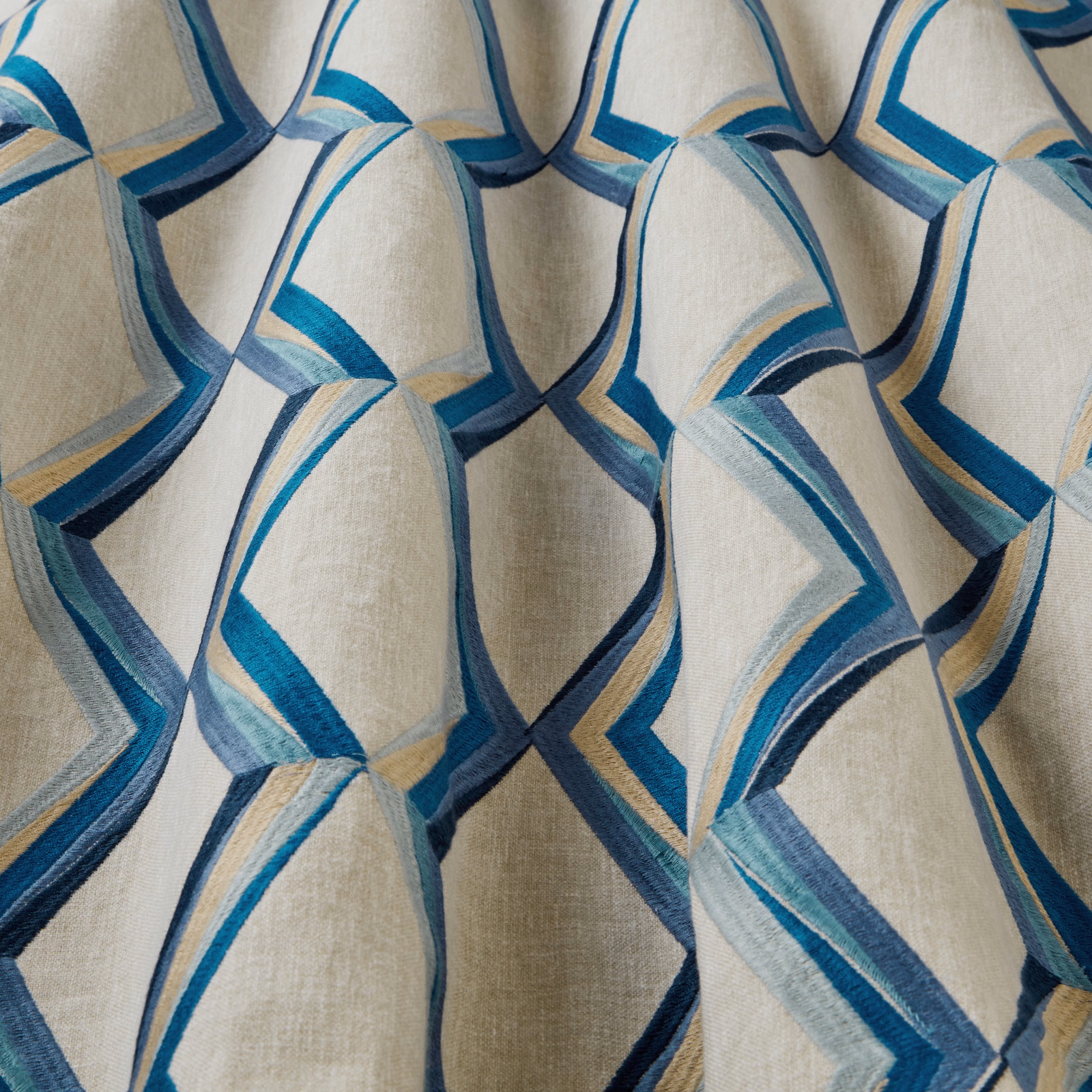Cream ground fabric with raised wavy geometric bands in teal, aqua, navy and gold