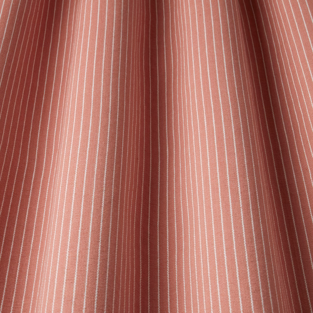 Raspberry pink cotton fabric with fine vertical white pinstripes and soft folds