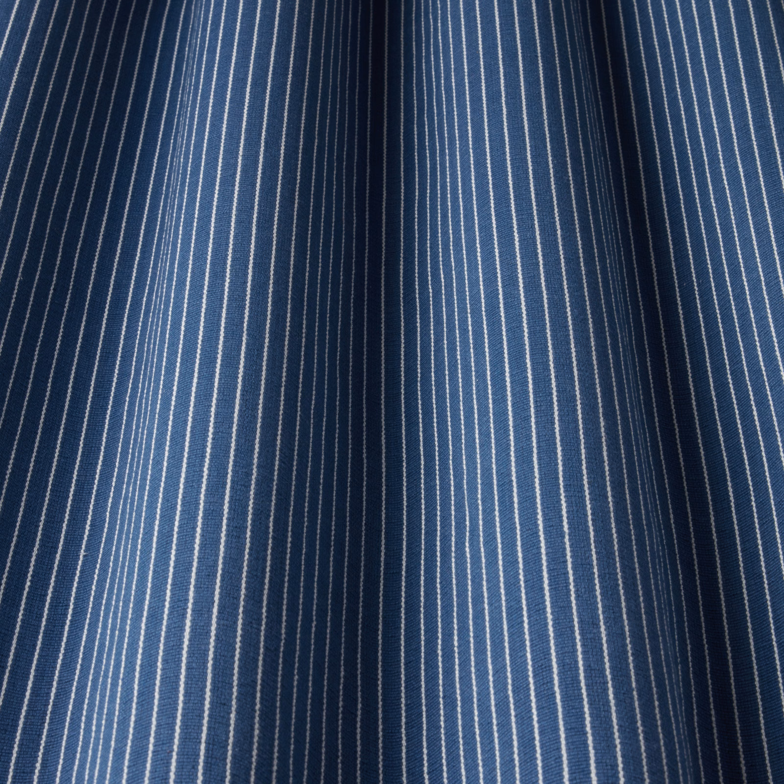 Deep navy cotton fabric with fine vertical white pinstripes and a crisp woven texture.