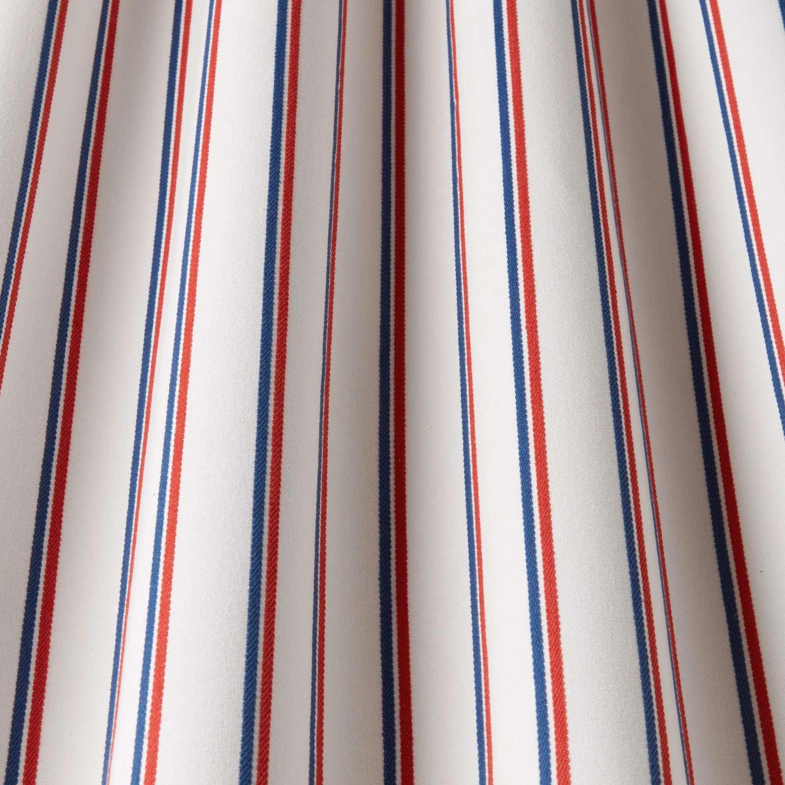 White cotton fabric with narrow navy and red vertical stripes
