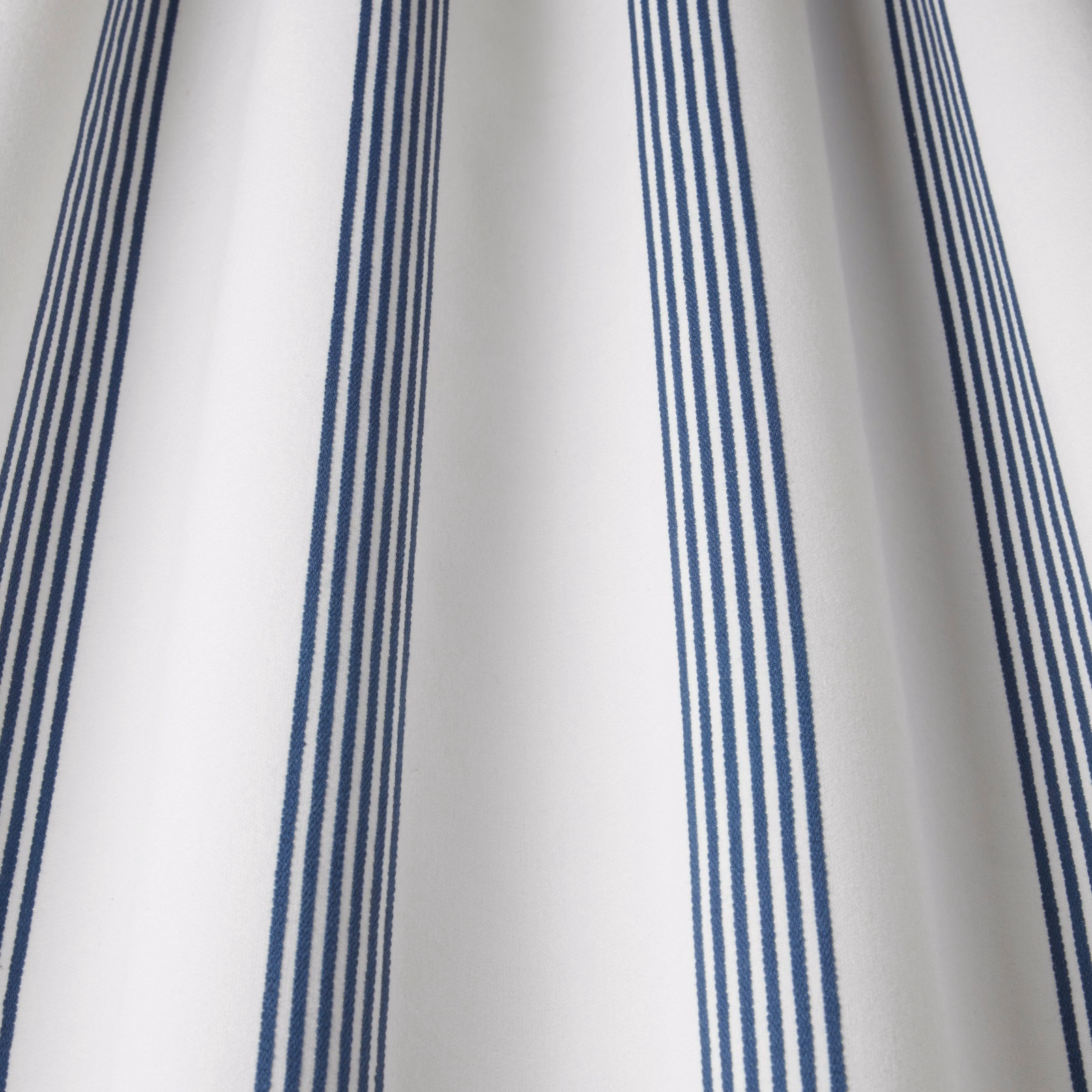 White cotton fabric with vertical navy stripe groups and a smooth woven finish