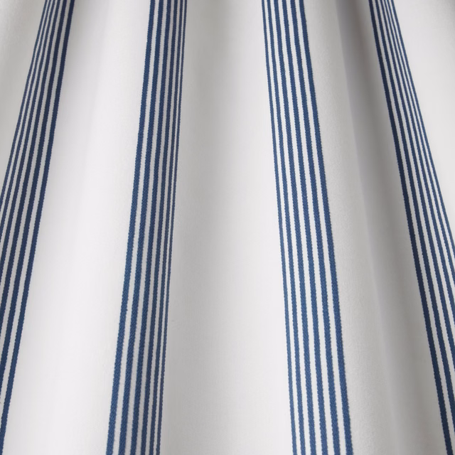 White cotton fabric with vertical navy stripe groups and a smooth woven finish