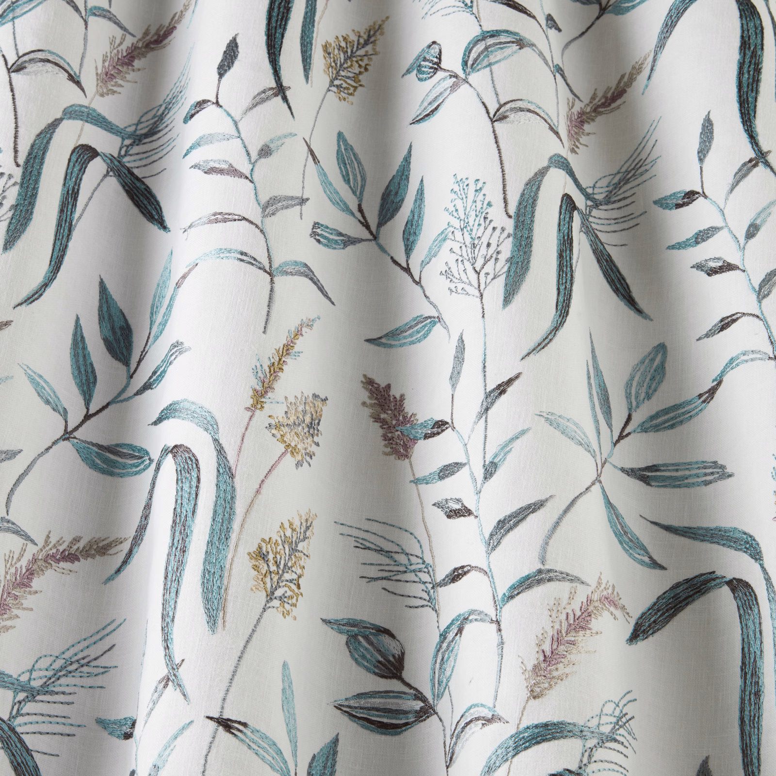 Light cotton fabric with teal and blue botanical stems on a pale ground