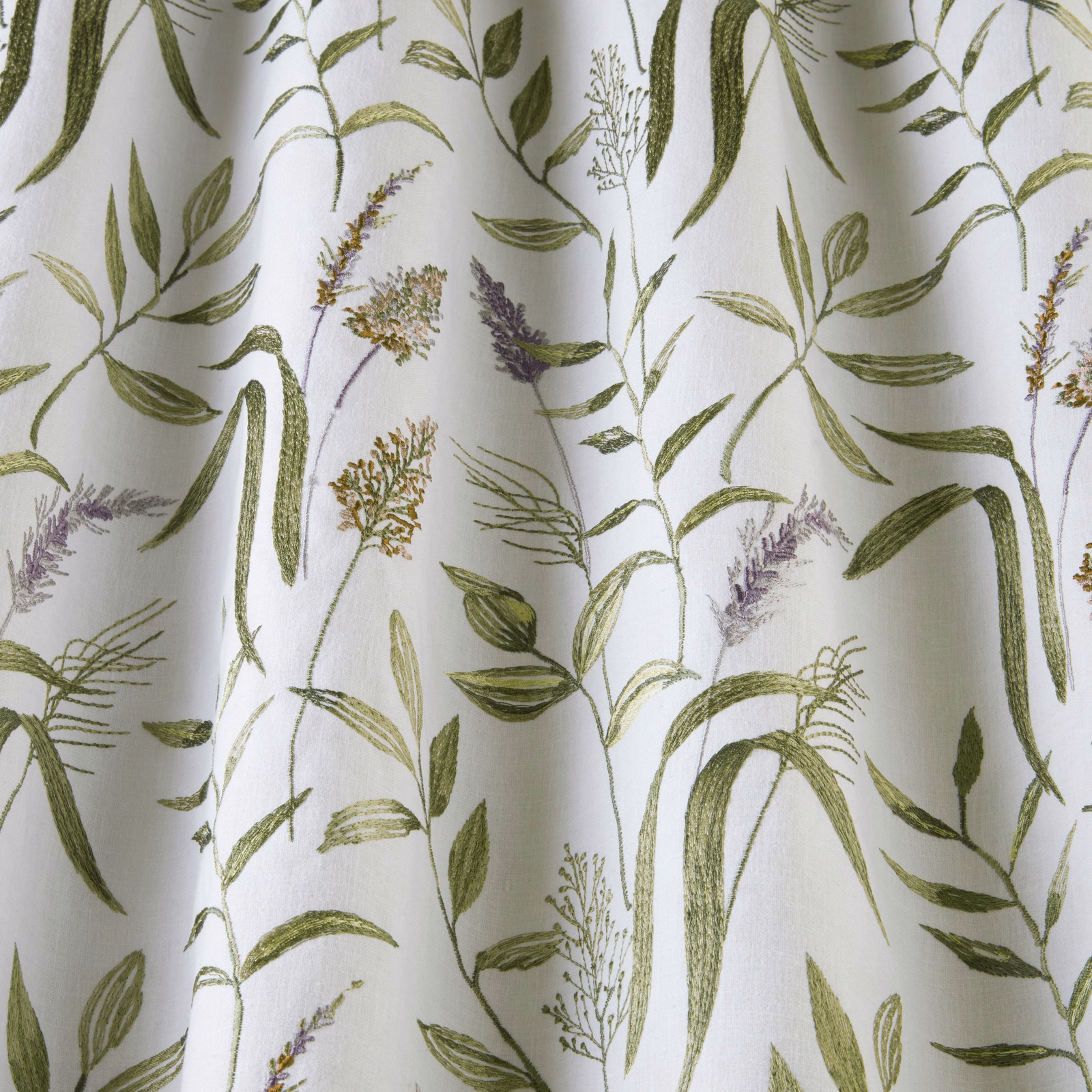 White cotton fabric with sage green botanical stems and lilac flower sprigs
