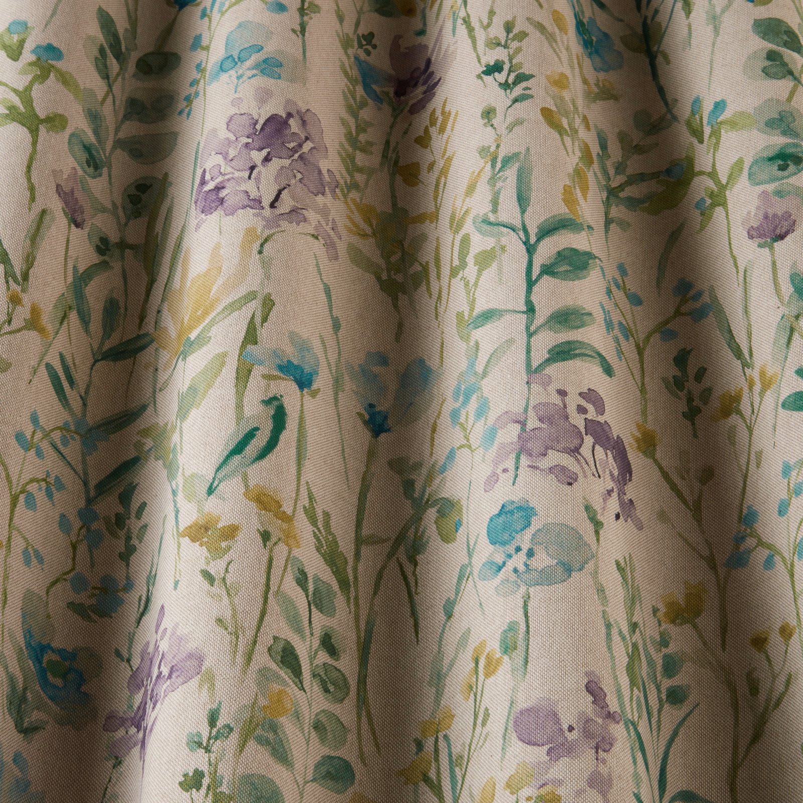 Printed cotton fabric with jade green floral stems, lilac blooms and aqua accents on a pale ground