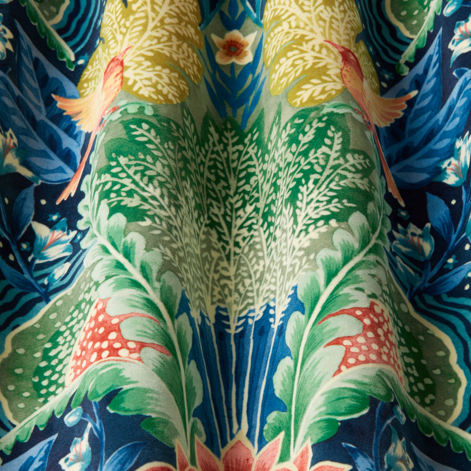 Close-up of a bold botanical fabric with midnight blue ground and vivid green leaves