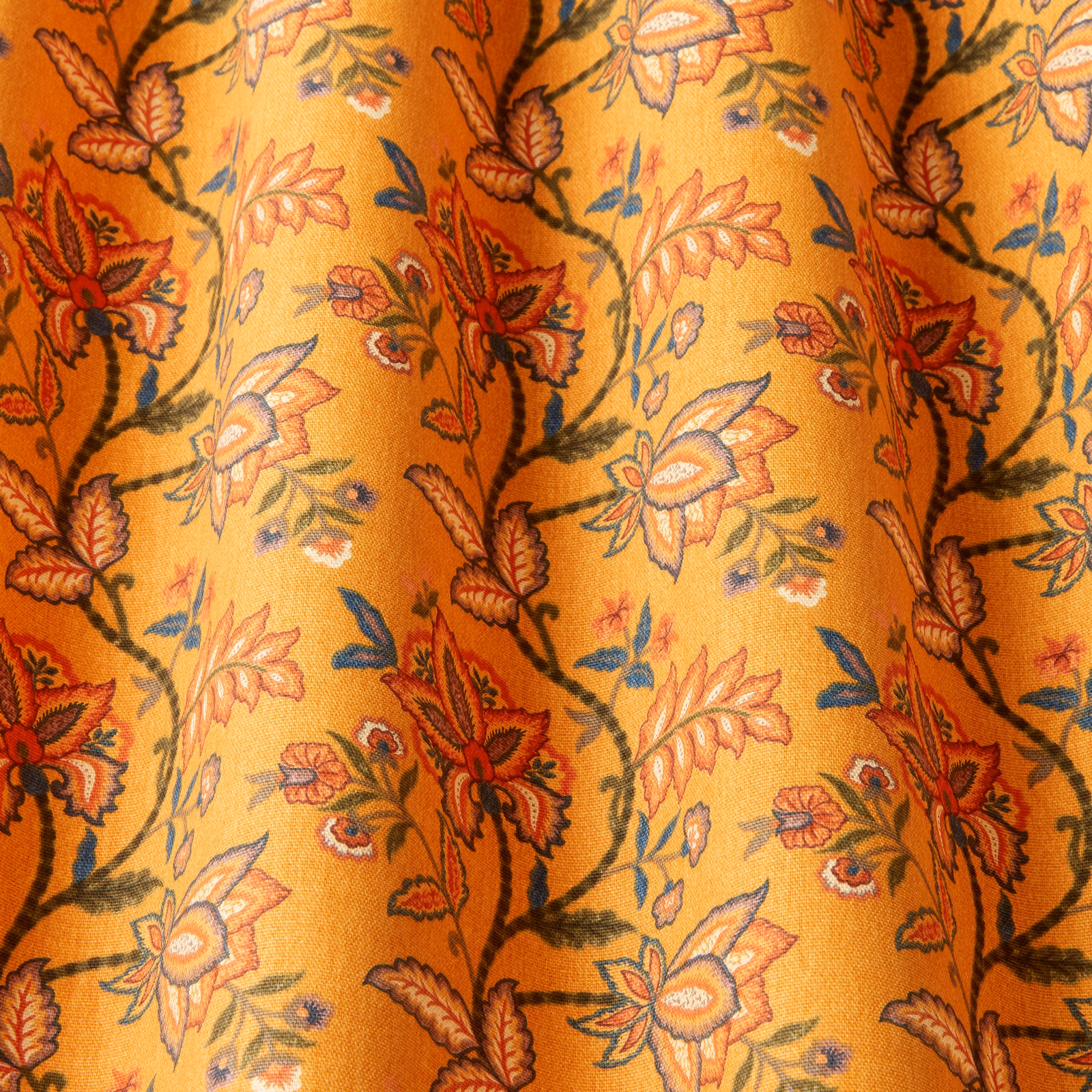 Golden cotton fabric with winding floral vines in red, green and blue