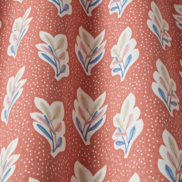 Coral terracotta fabric with white speckle and cream leaf motif with blue accents